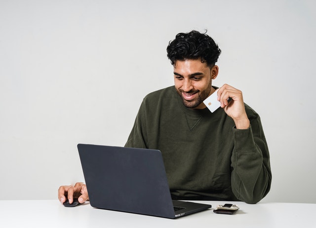 Man Holding Credit Card In Front Of Computer