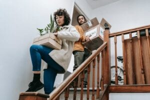 Brother Helping Out Sister By Carrying Boxes Down The Stairs To Move Out Of Her Parents House