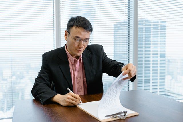Businessman Flipping Through Pages On A Notebook In An Office For Article How Much Property Mangers Earn